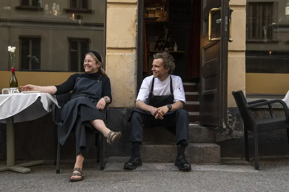Two people sitting outside a restaurant.