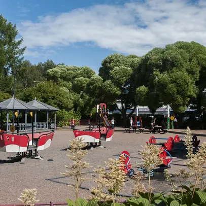 Playground equipment and children in a green environment.