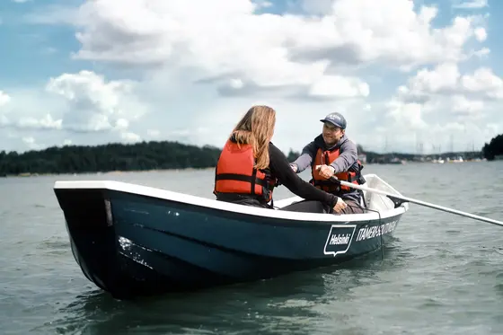 A man rowing a city boat and a woman sitting in the boat.