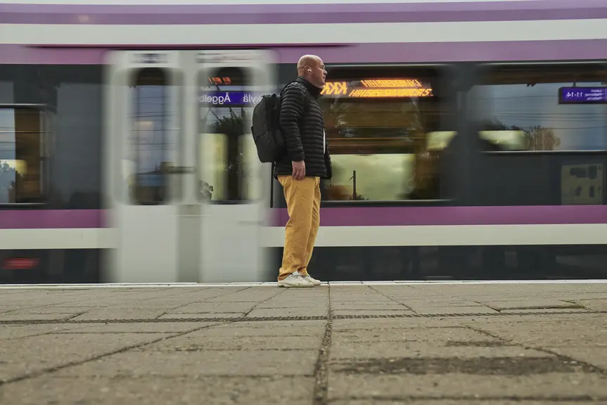  A person is standing at a commuter train station.