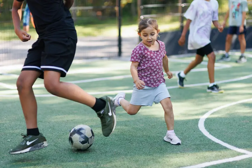 Barn som spelar fotboll på en konstgräsplan.