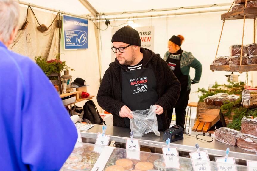 En försäljare med svart mössa bakom fiskdisken.