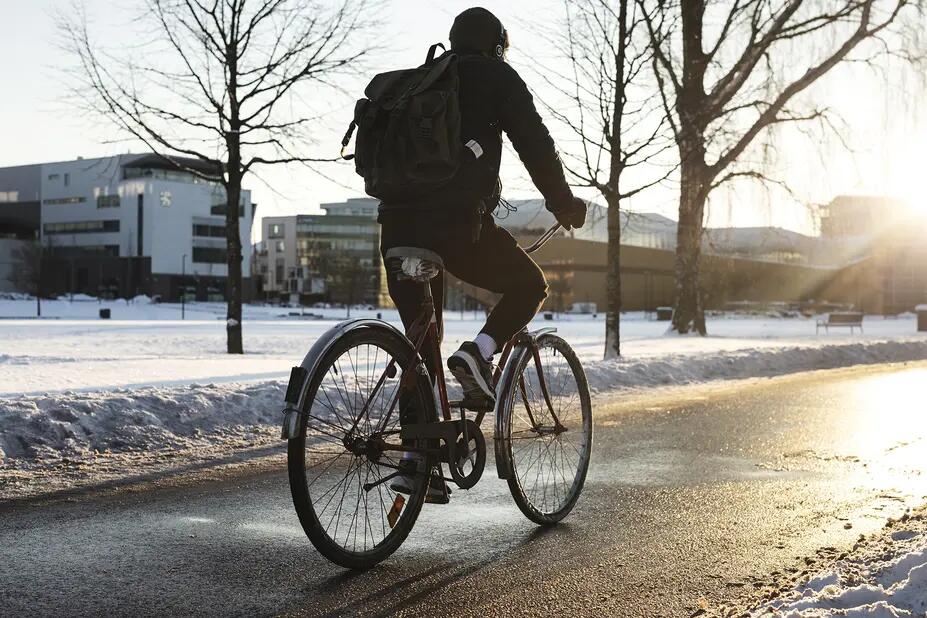 Pyöräilijä takaapäin kuvattuna talvella.