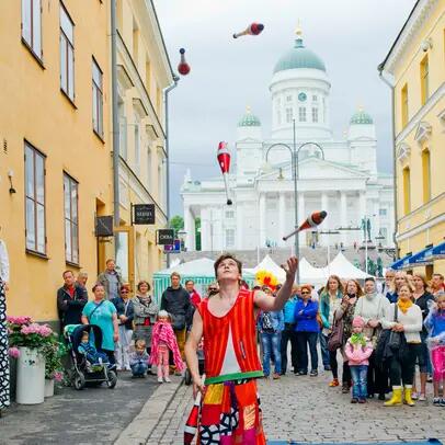 En publik som tittar på en jonglörs trick i Helsingfors torgkvarter.