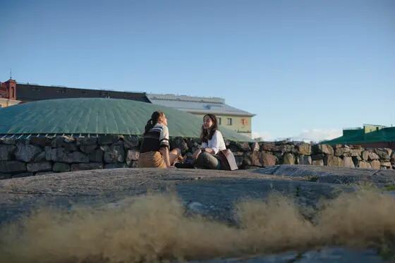 Two people sitting in the summer evening sun outside the Temppeliaukio Church.