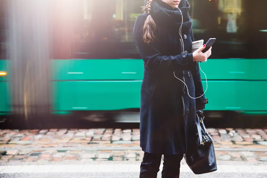 En person tittar på sin telefon vid en busshållplats.