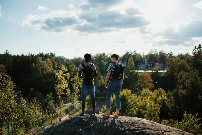 Kaksi ihmistä aurinkoisella ilmalla kalliolla.
