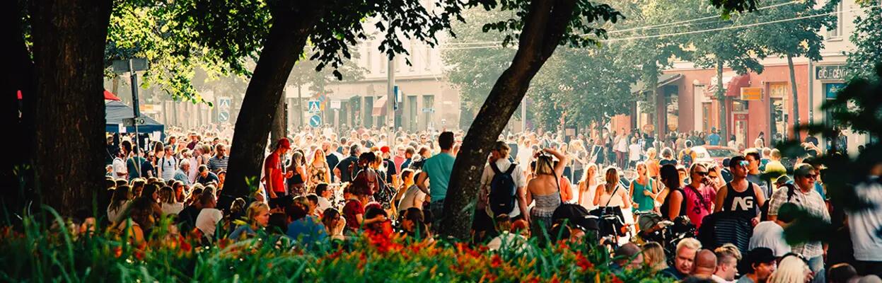 Kalio Block Partyssä kaupunkipuistossa paljon ihmisiä kesäpäivänä kuuntelemassa musiikkia puiden varjossa.