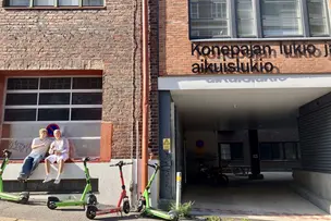 Opiskelijoita istumassa Konepajan lukion sisäänkäynnin edessä.