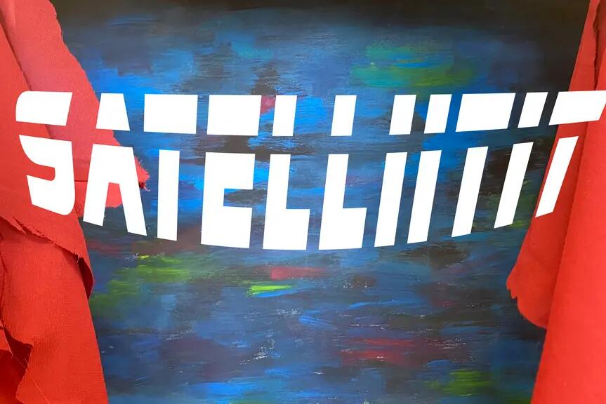Satelliitit teksti sinisen maalauksen ja punaisten esirippuverhojen edessä.