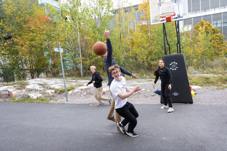 Opiskelijat pelaavat pihalla koripalloa
