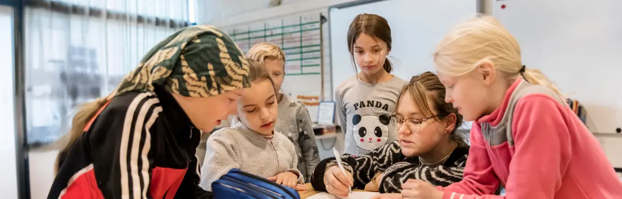 Lapset luokassa opettajan kanssa.