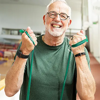 En äldre man gymnastiserar glatt med hjälp av ett motståndsband.