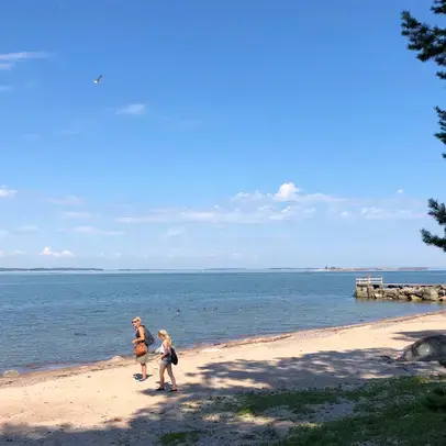 Henkilöt kulkevat hiekkarannalla.
