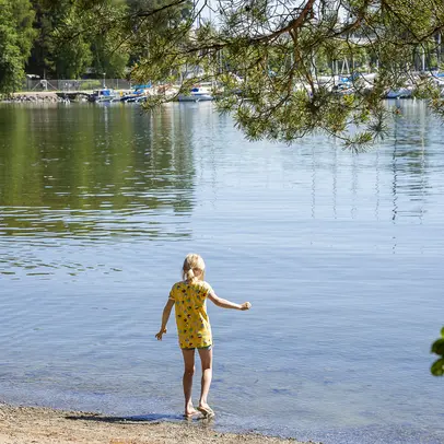 Lapsi kävelle hiekkarannan rantaviivan tuntumassa kohti vettä.