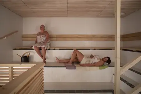 Two people relaxing in a sauna, with towels wrapped around them.