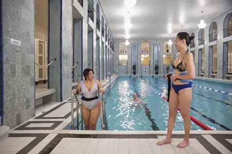 Swimmers with aqua jogging belts standing by the pool.