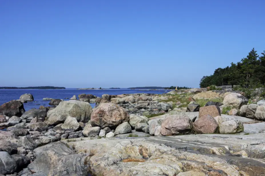 Kaunissaaren kivikkoista rantaa ja sinitaivas.