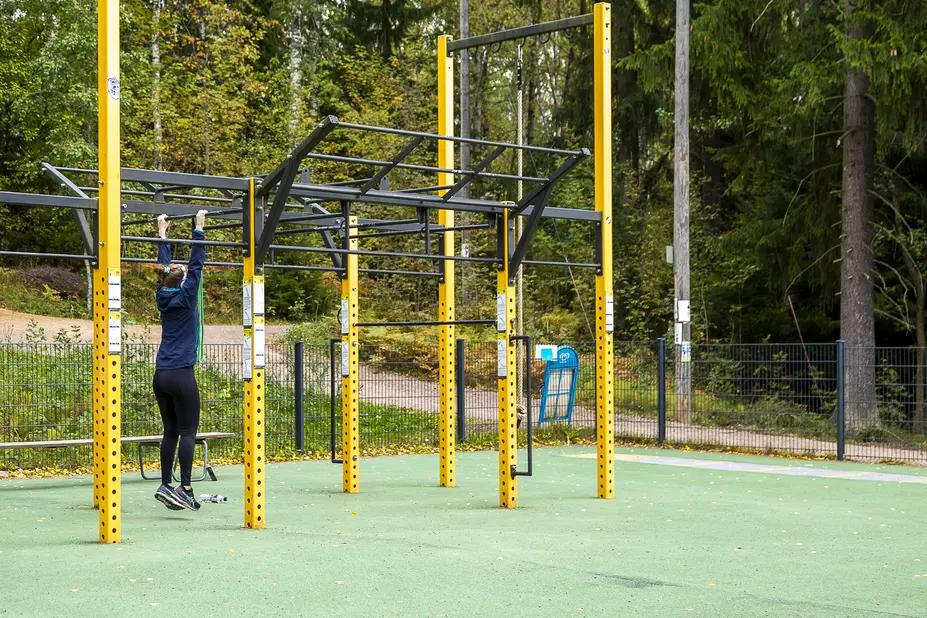Henkilö Pirkkolan ulkokuntosalin monitoimilaitteessa.