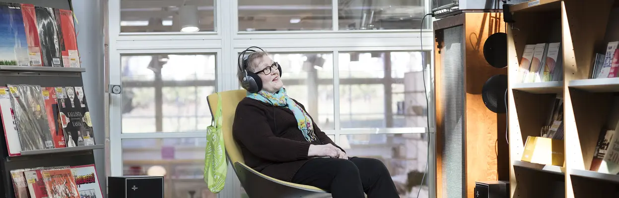 Henkilö kuuntelee musiikkia kirjastossa.
