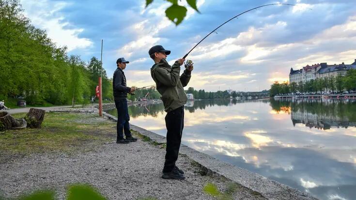 Kaksi nuorta kalastaa Kaisaniemenrannassa.