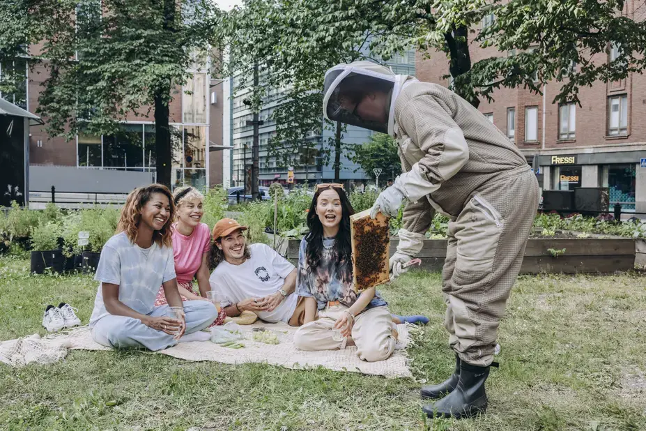 Mehiläistarhuri esittelee mehiläiskennoa puistossa.